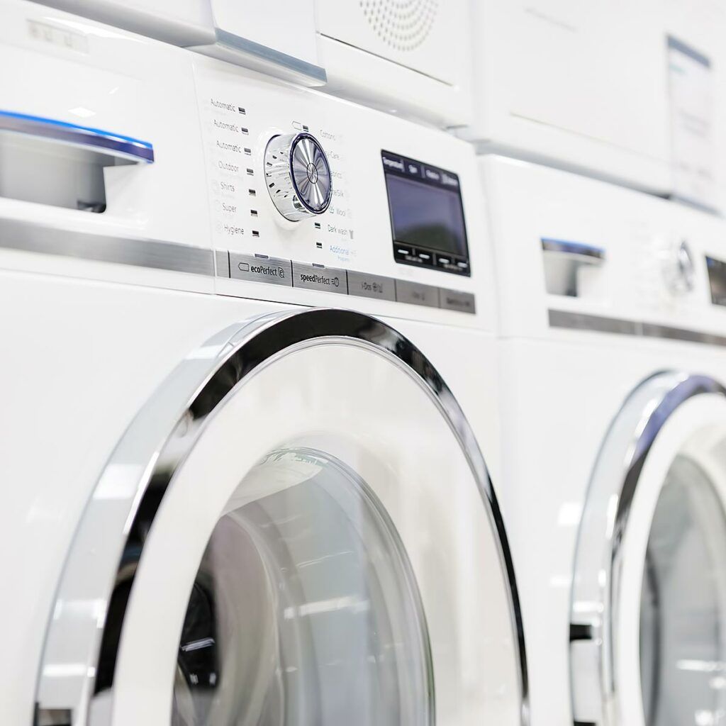 Nahaufnahme von zwei weißen Waschmaschinen mit Drehregler und Display.