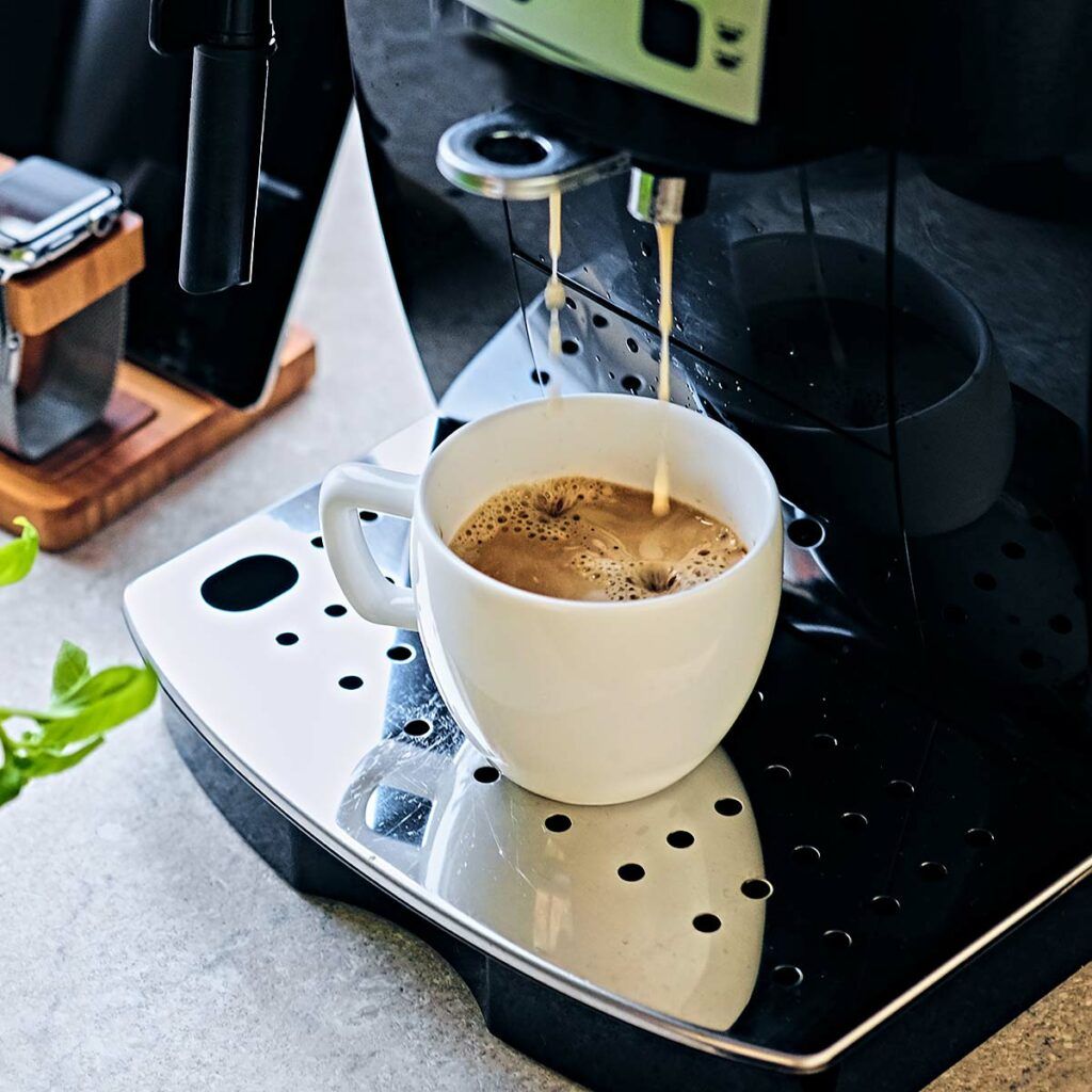 Espressomaschine füllt eine weiße Tasse mit frisch gebrühtem Kaffee.